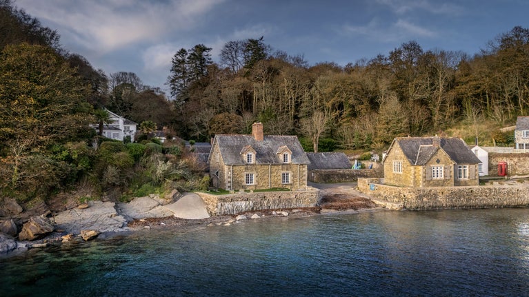 Durgan Quay Cottage (on the left), joined to Durgan Beach Cottage and with Durgan Old School House across the slipway, Cornwall